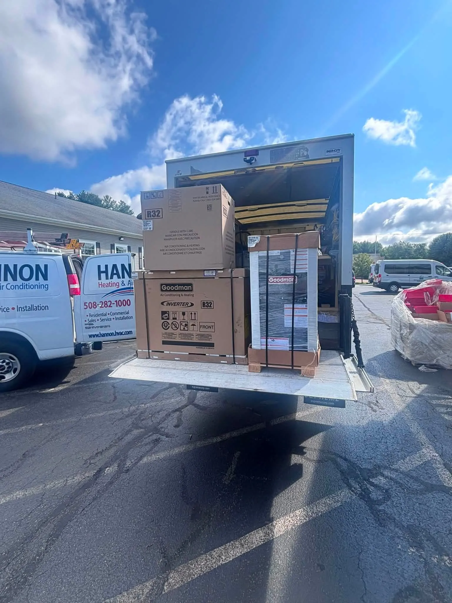 Hannon box truck liftgate loaded with equipment, with branded vans and the shop behind
