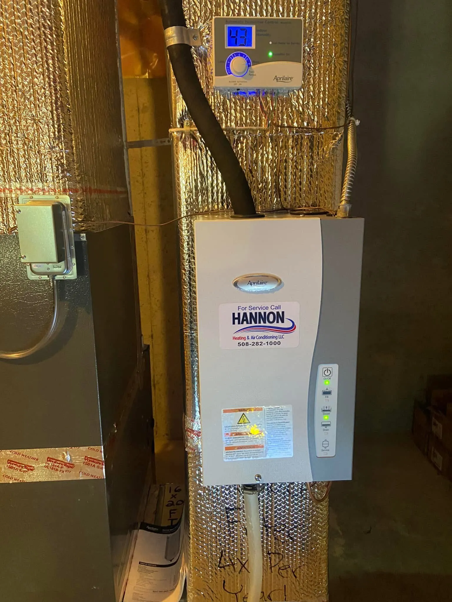 Aprilaire whole-home humidifier installed on ductwork with a Hannon service sticker