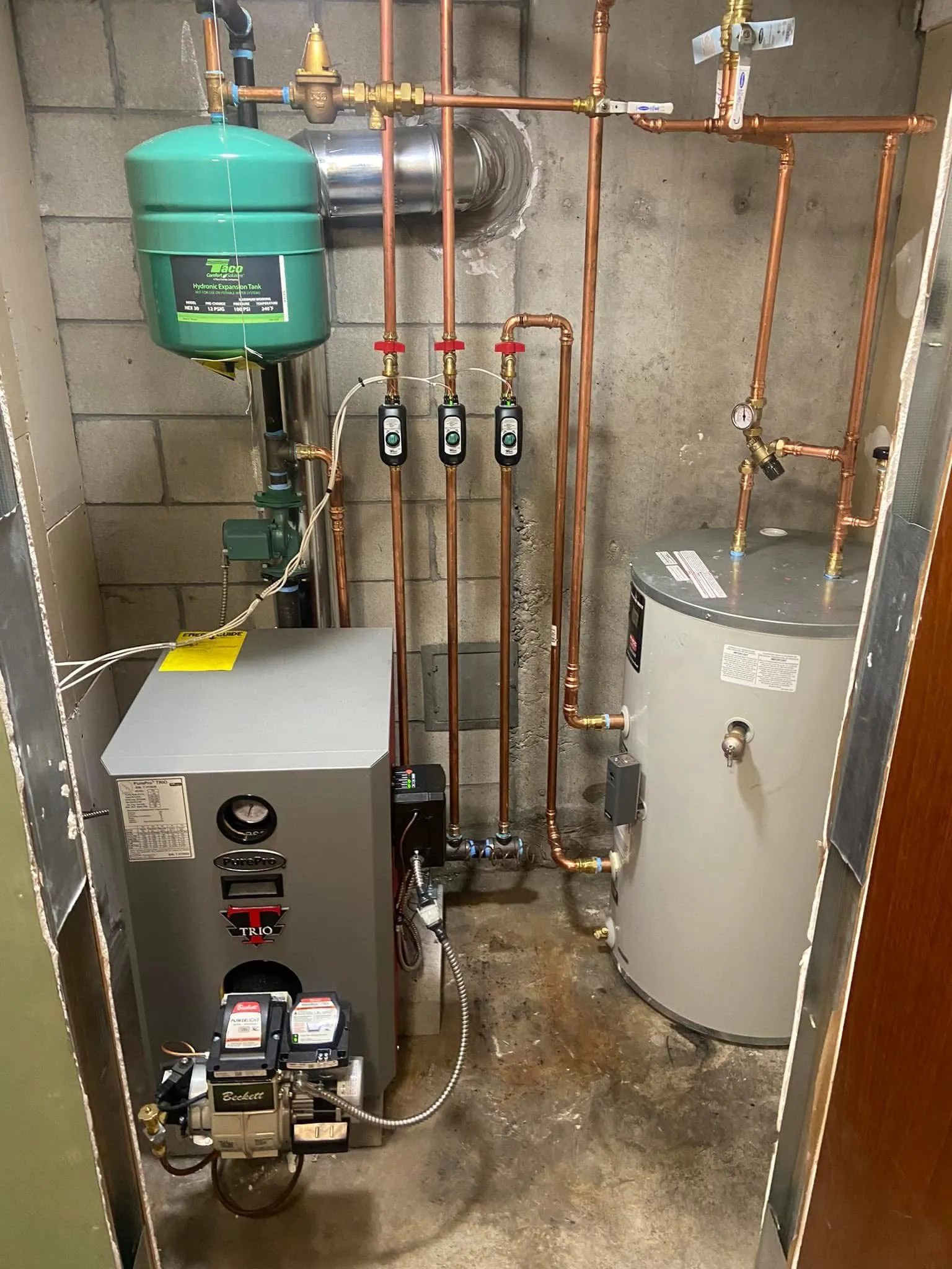 PurePro Trio oil boiler with a Beckett burner installed by Hannon in a tight utility closet, with dense copper piping and an indirect water heater