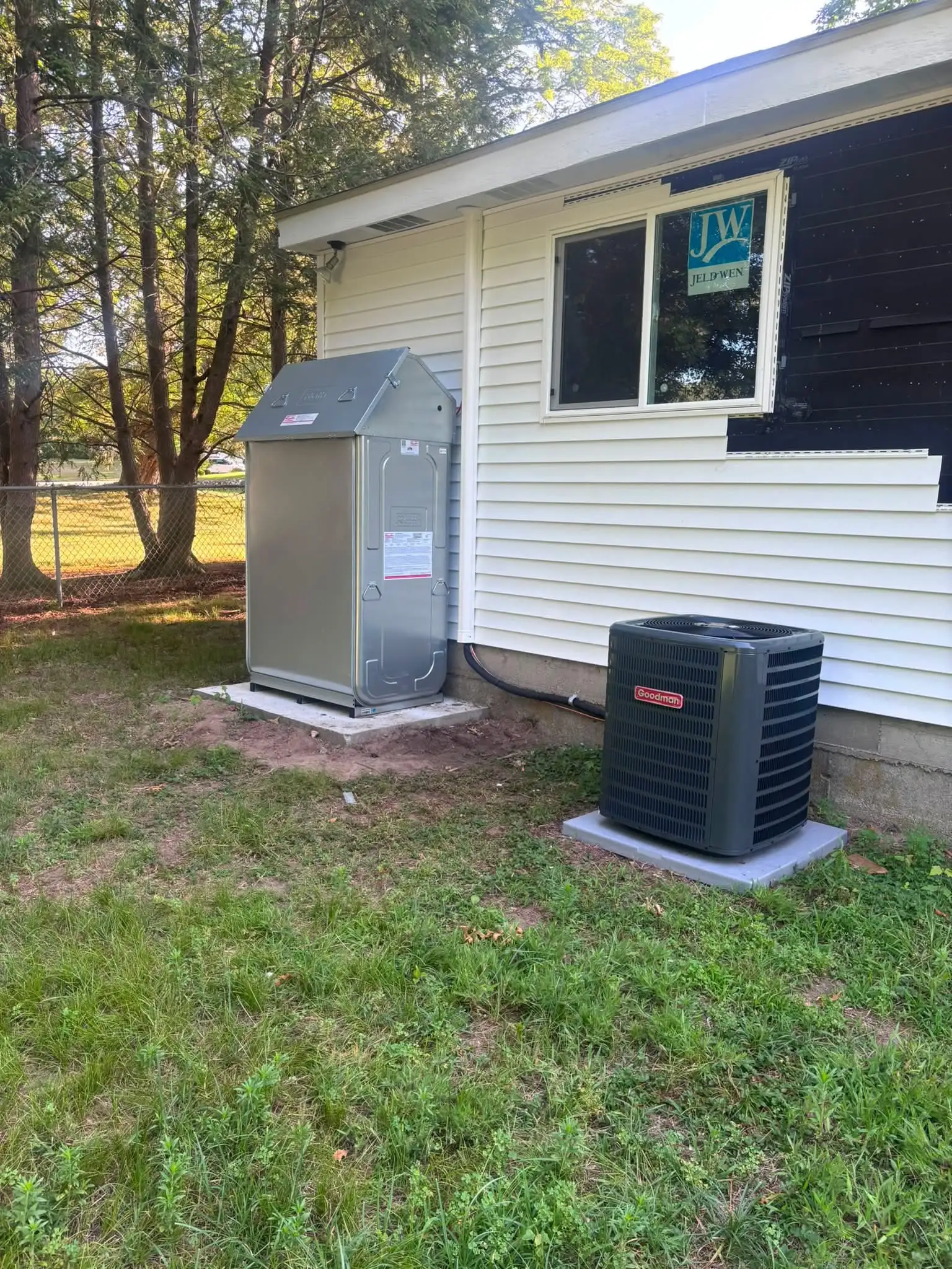 Outdoor oil tank installed by Hannon in a galvanized protective enclosure, with a Goodman AC condenser alongside